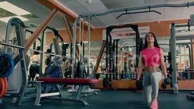 运动的年轻女子在健身房用哑铃做运动。 4千克
